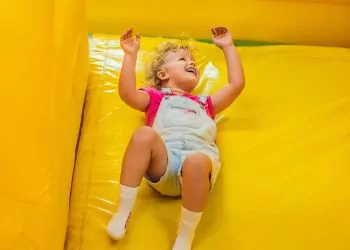 Girl playing on yellow inflatable slide